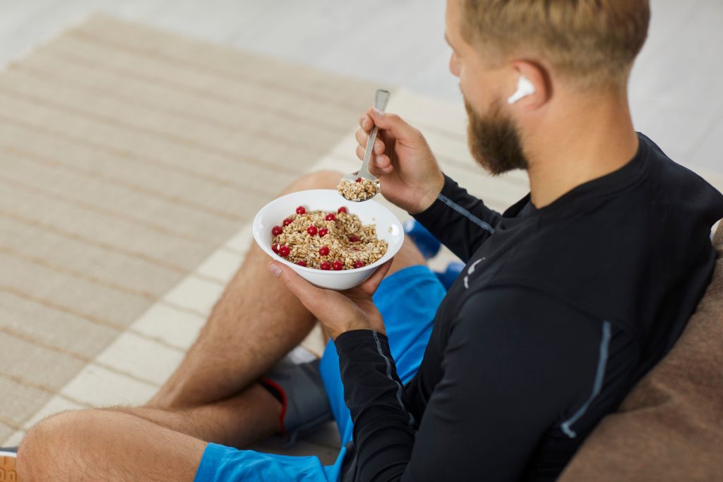 Homem no sofá comendo uma alimentação vegetariana para ir a academia.