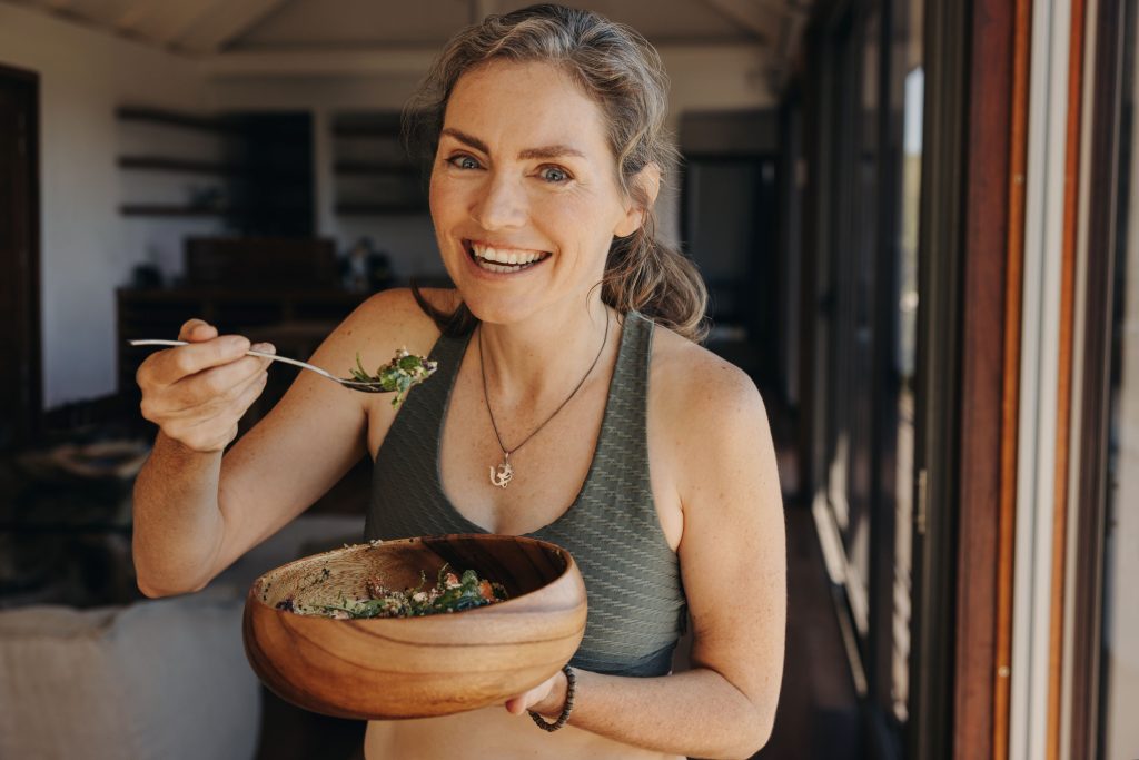 Mulher sorridente comendo uma alimentação vegetariana para ir a academia