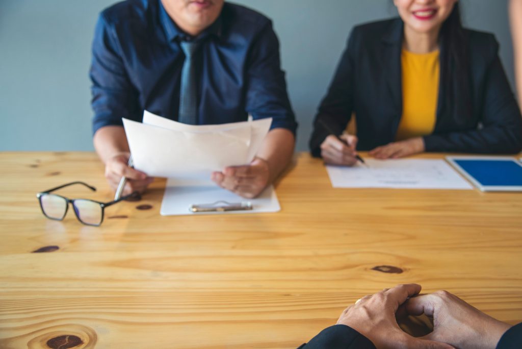 Pessoas de negócios em entrevista de emprego com o responsável de RH, apertando as mãos no escritório, com rostos sorridentes de felicidade. Gerente empresária entrevistando um funcionário frente a frente, sentados na sala de reunião. Conceito de entrevista de emprego.