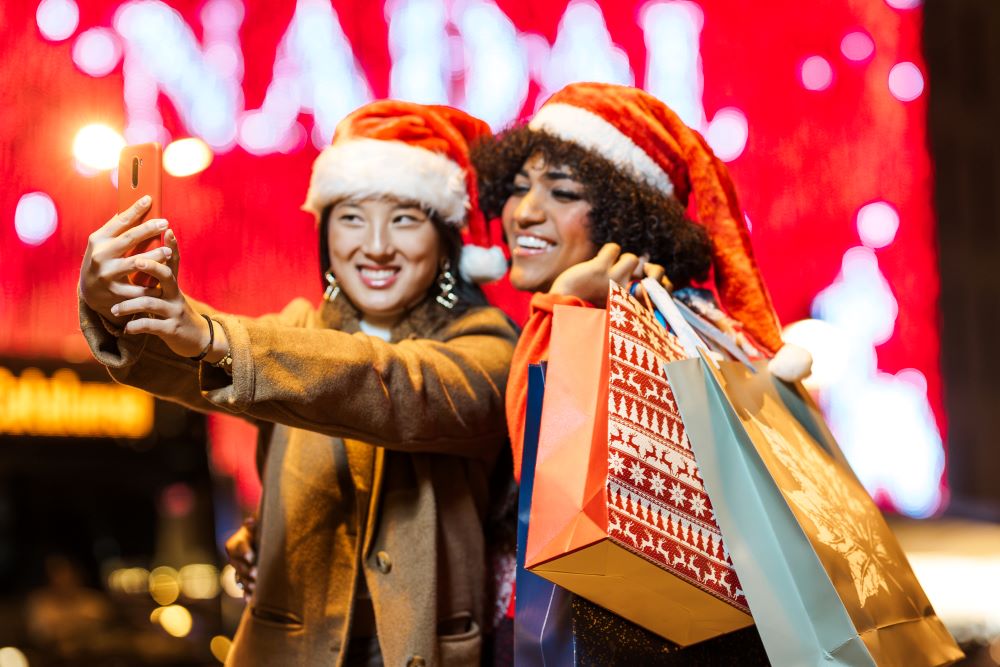 Duas mulheres fazendo self com gorro de natal na cabeça representando época do natal